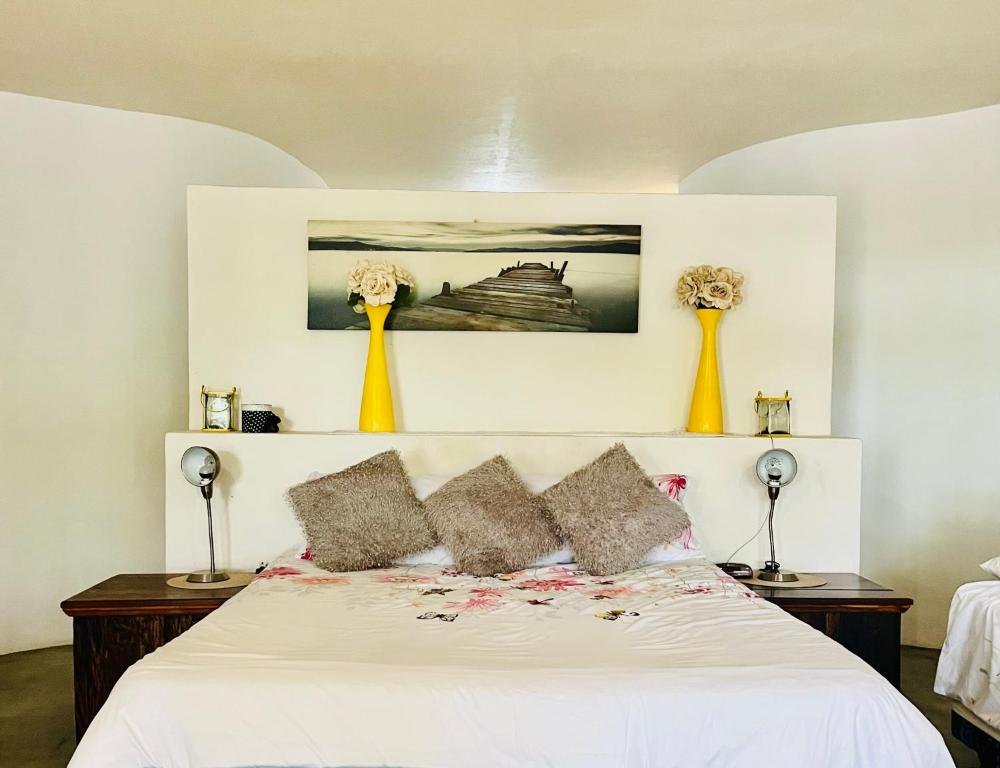 a bedroom with a bed with white sheets and yellow vases at Nandina Self Catering in Hazyview