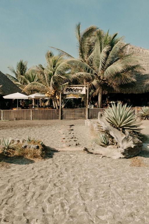 a beach with palm trees and footprints in the sand at Cocorí Lodge Paredón in El Paredón Buena Vista