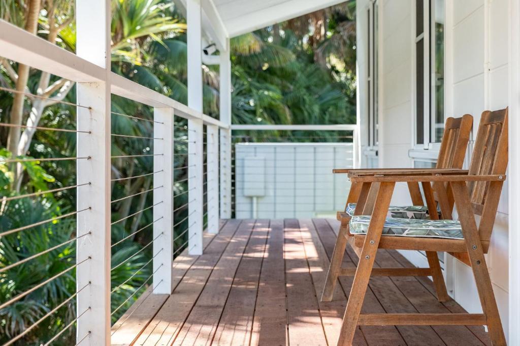 a porch with a wooden chair and a table at Boo's Place in Blueys Beach