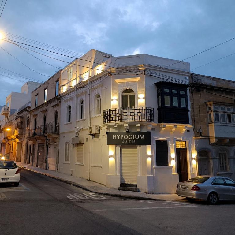 a white building with a sign on it on a street at Hypogeum SuiteStudio in Ħal Saflieni