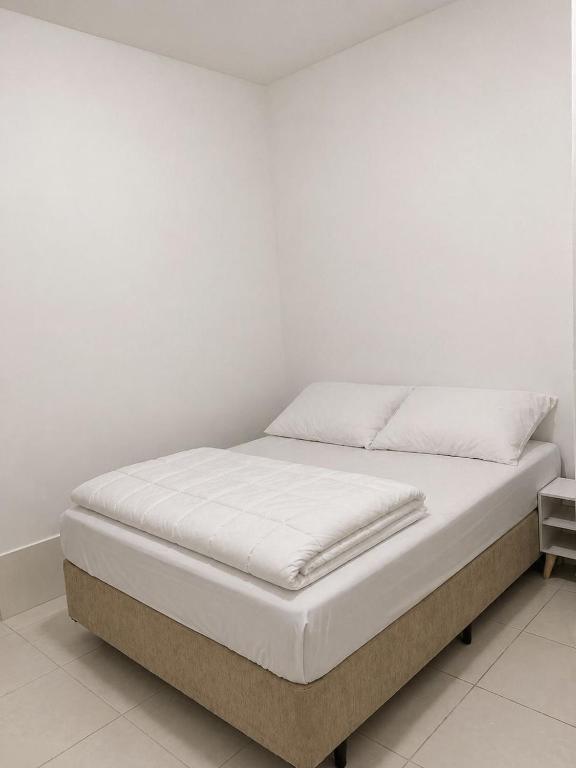 a bed in a room with a white wall at Heyco camping e hospedaria in Cabo Frio