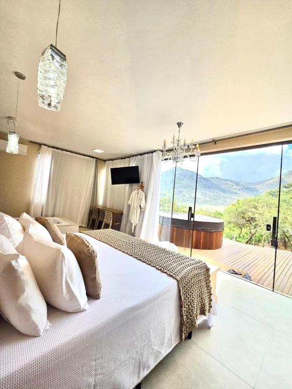 a bedroom with a large bed and a large window at Euetu na Lapinha da Serra in Santana do Riacho
