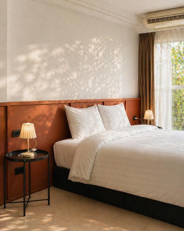 a bedroom with a large bed and a window at Quicky Stay Hotel Suphanburi in Suphan Buri