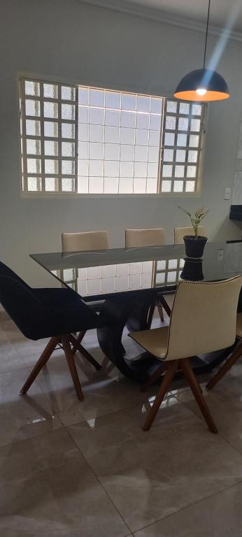 a dining room with a glass table and chairs at Casa Flórida in Uberaba