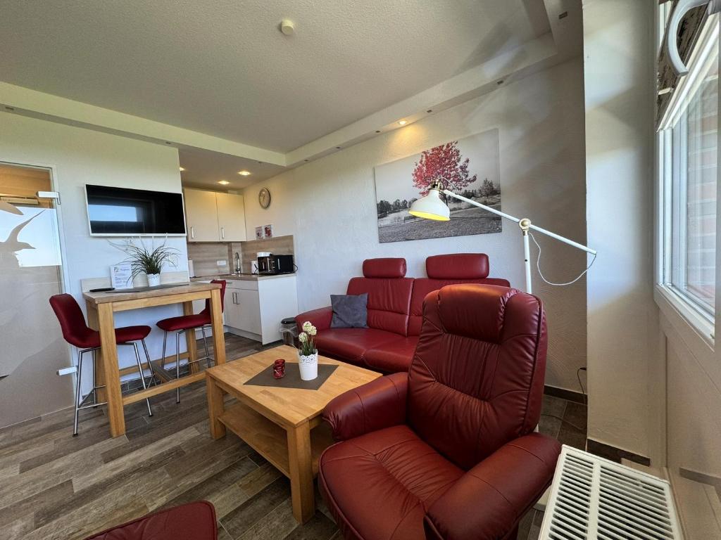 a living room with a red couch and a table at Tief 10 Neptun mit Internet 607 in Wangerland