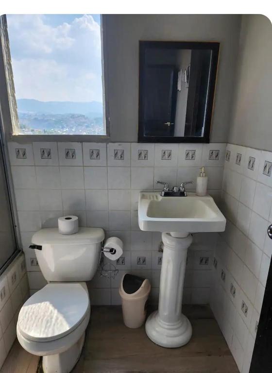 a bathroom with a toilet and a sink and a window at apartamento terracota in Tegucigalpa