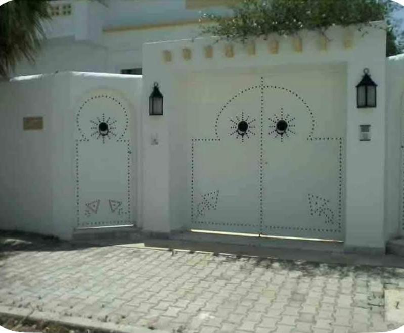 a white fence with two gates on a driveway at Maison du prince in Yasmine