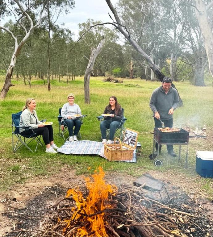 a group of people sitting around a fire at Woodlands - Vineyard setting in Penwortham