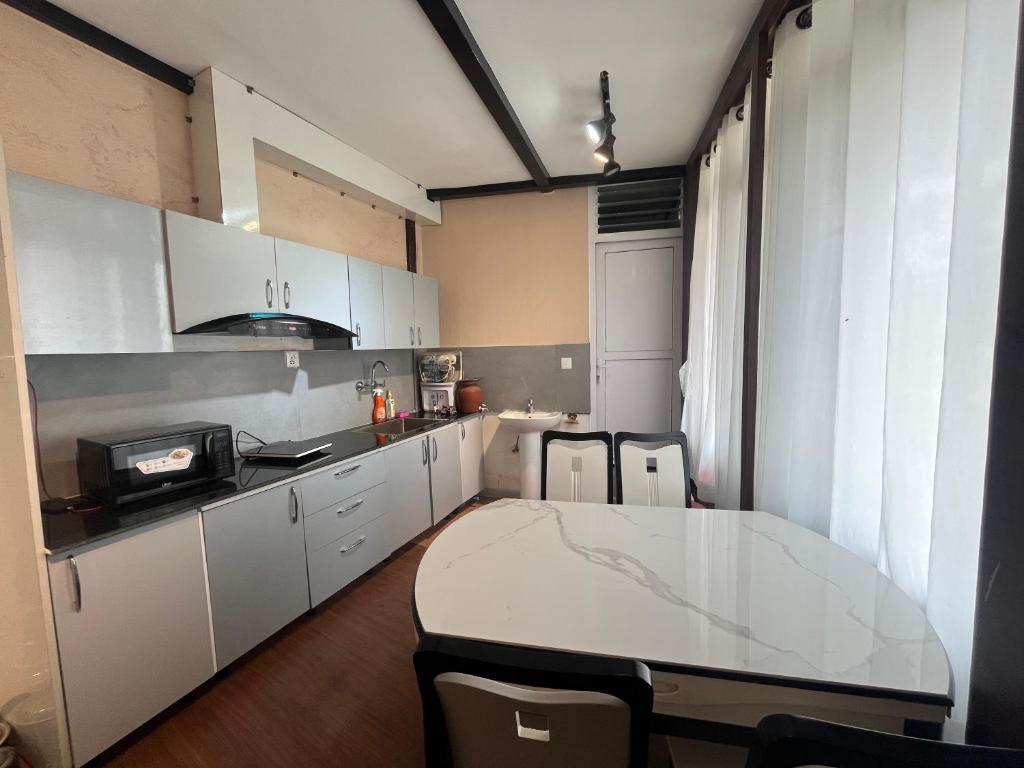 a kitchen with white cabinets and a table and chairs at Our furnex homes in Pātan