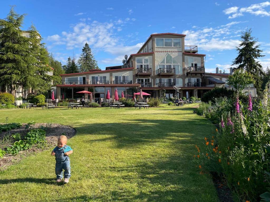 a little boy standing in the grass in front of a building at Old Alcohol Plant in Port Hadlock