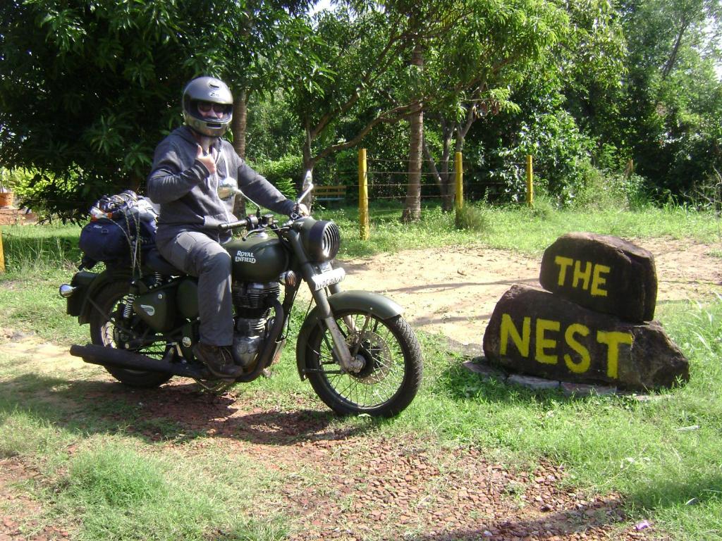 Un uomo sta guidando una moto accanto a un cartello di The Nest a Mahiyangana