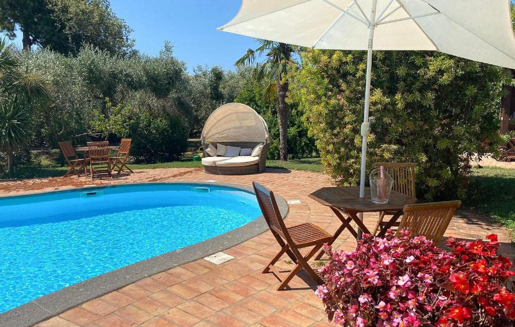 a pool with a table and an umbrella and a table and chairs at Lovely Home In Tarquinia in Tarquinia