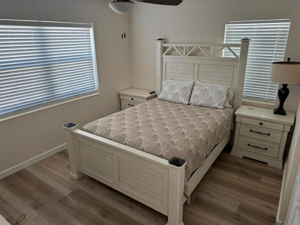 a bedroom with a white bed and two windows at Coastal Sun Retreat in St. Pete Beach