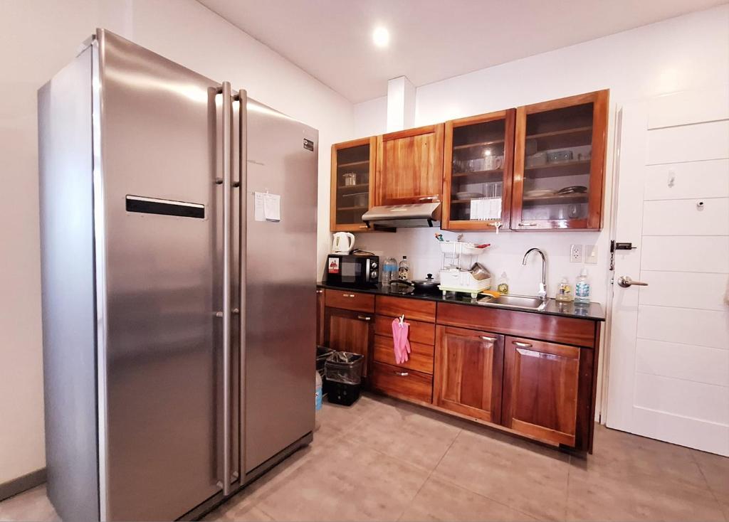 a kitchen with a stainless steel refrigerator and wooden cabinets at Scandi Apartment Boracay by Simple Realty Management in Boracay