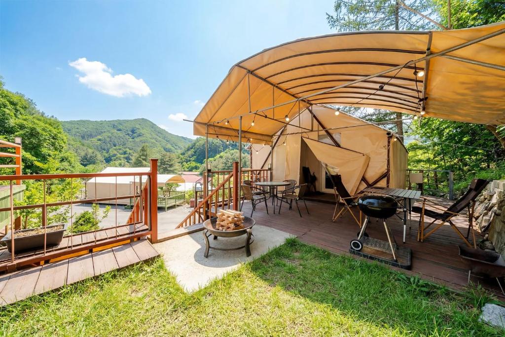 a yurt with a table and a grill on a deck at Pocheon Terrace 527 Campground in Pocheon