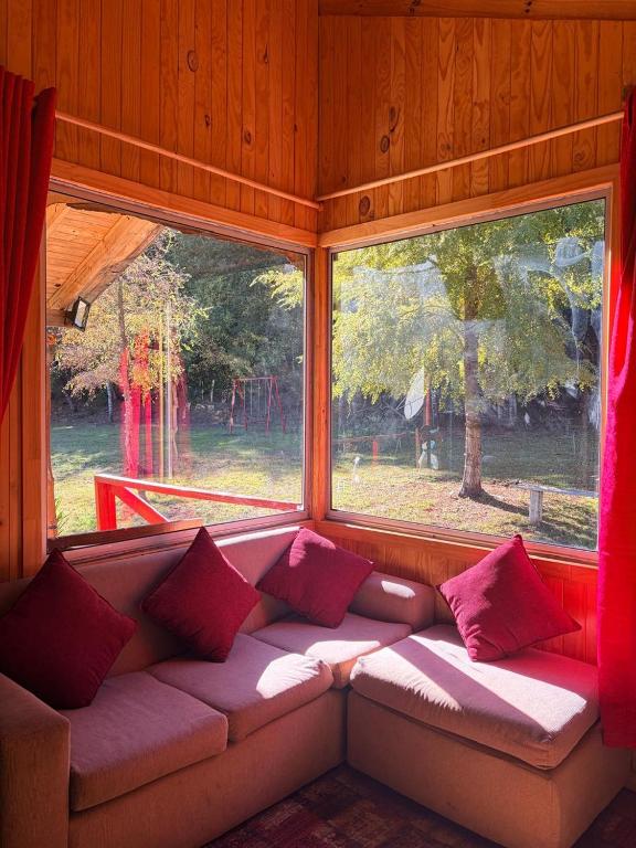 a couch sitting in a room with two windows at Refugio El Rocio lodge tinaja,piscina,bosque in Nacimiento