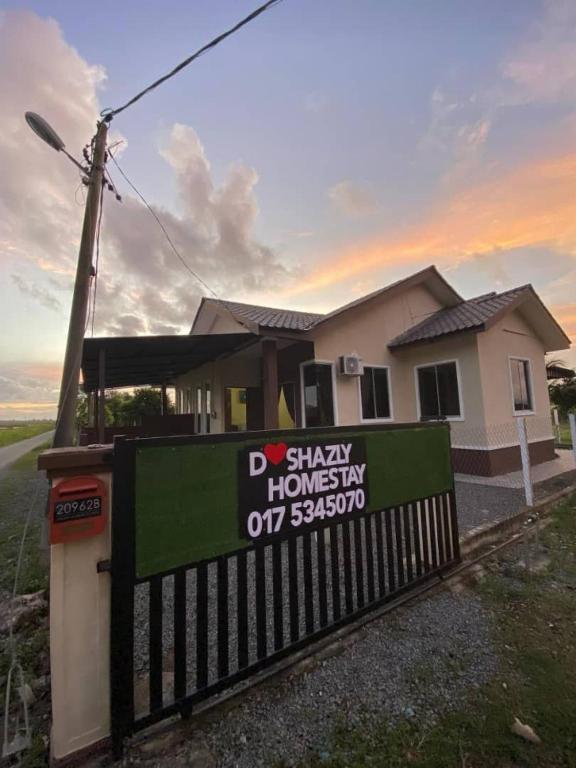 a house with a sign in front of a fence at D'Shazly Homestay Village in Arau