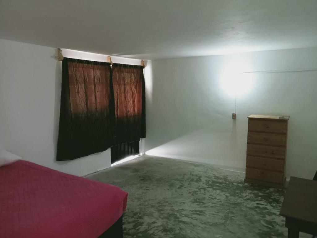 a bedroom with a bed and a dresser and a window at Habitación cerca del centro de Tlaxcala in Ocotlán