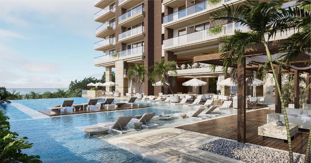a hotel swimming pool with lounge chairs and palm trees at Nuruma Suites by Avia Suites in Santa Marta