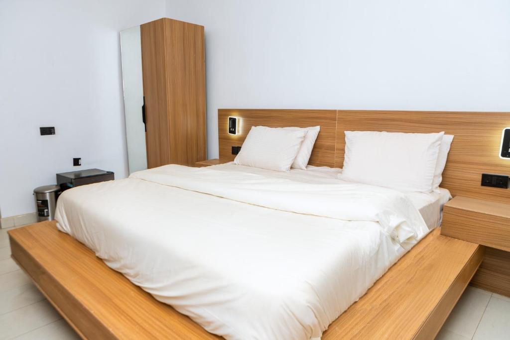 a bedroom with a large white bed with a wooden headboard at Star Hotel & Suites in Abuja