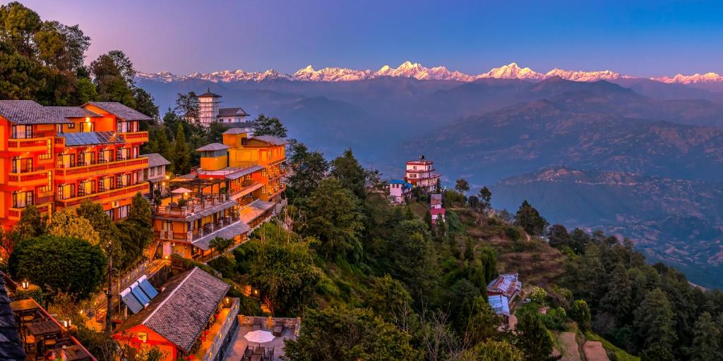a group of buildings on a hill with mountains in the background at Hotel Country Villa in Nagarkot