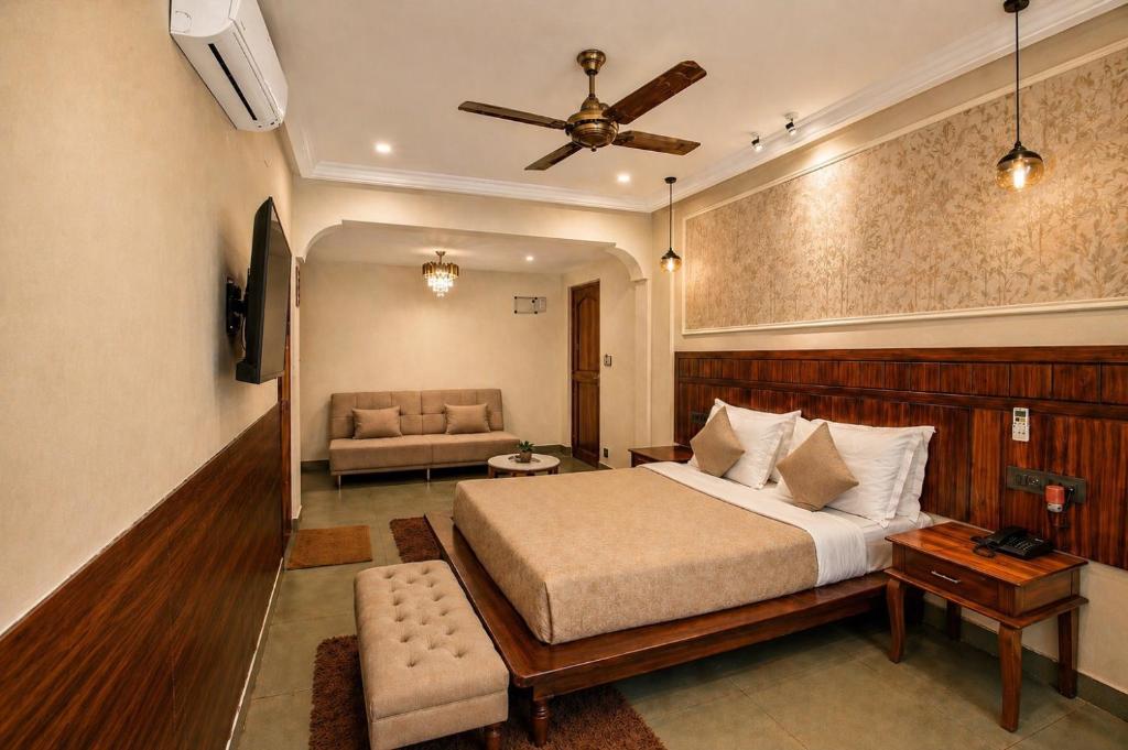 a bedroom with a bed and a couch and a ceiling fan at Dimaru Boutique Hotel in Calangute