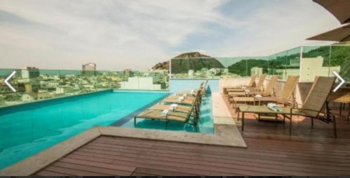 a swimming pool with lounge chairs and a view of the ocean at Sant copacabana in Rio de Janeiro
