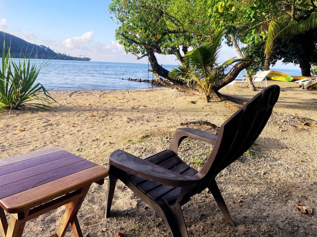 a wooden chair and a table on a beach at Fare Oviri Lodge in Opoa