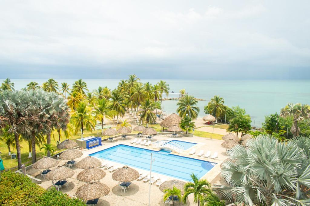 an aerial view of a resort pool with umbrellas and palm trees at Coveñas - Condominio Puntepiedra Hotel in Coveñas