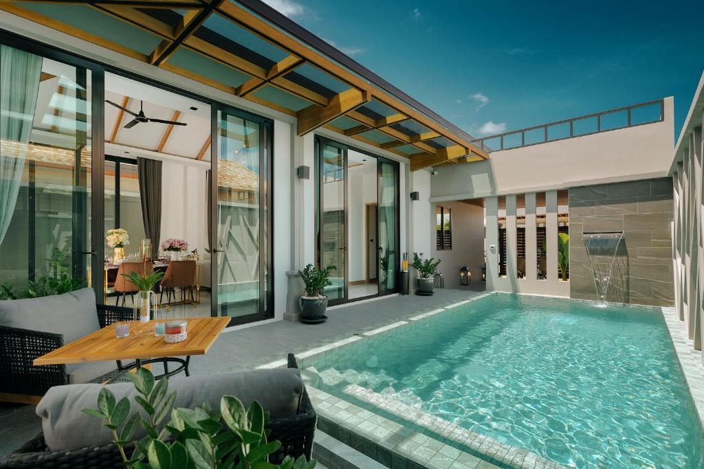 an indoor swimming pool in a house with a table at Rawayana Villas in Rawai Beach