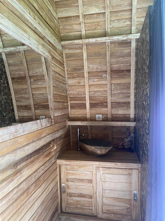 a bathroom with a sink and a wooden wall at Sari Lumbung Bungalow in Penginuman