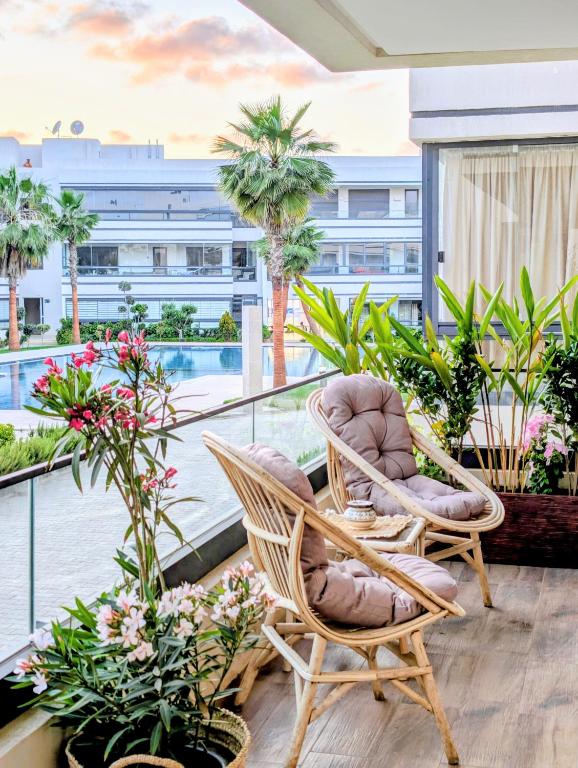 a balcony with chairs and plants and a view of a building at Pool view apartment, beach access, nature & quiet in Mansouria