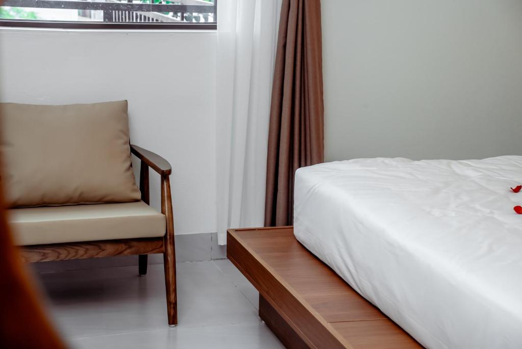 a bedroom with a bed and a chair and a window at Cát Boutique Hotel in Dong Hoi