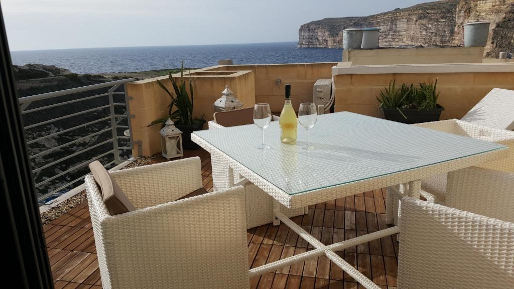 Biały stół i krzesła na balkonie z widokiem na ocean w obiekcie Kantra Residence w mieście Xlendi