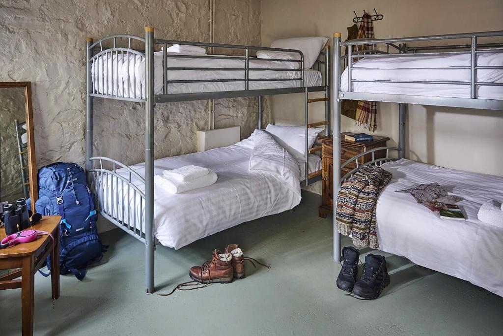 a room with two bunk beds and shoes in it at Drewe Arms Bunk Rooms in Drewsteignton