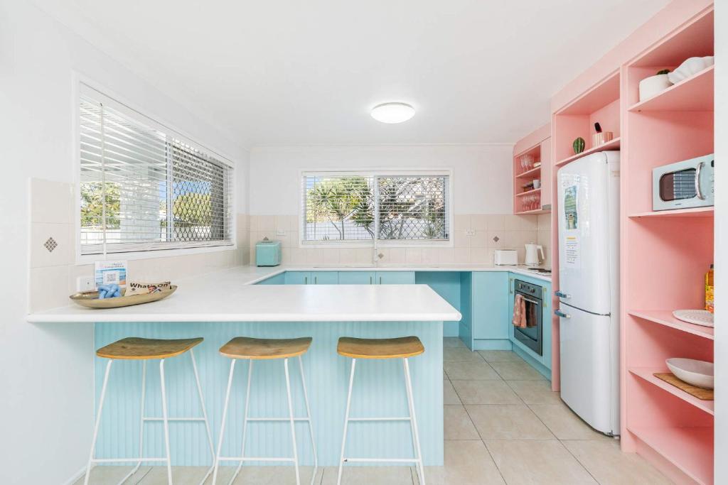a kitchen with a blue island and two stools at The Springs Villa 2 in Urangan