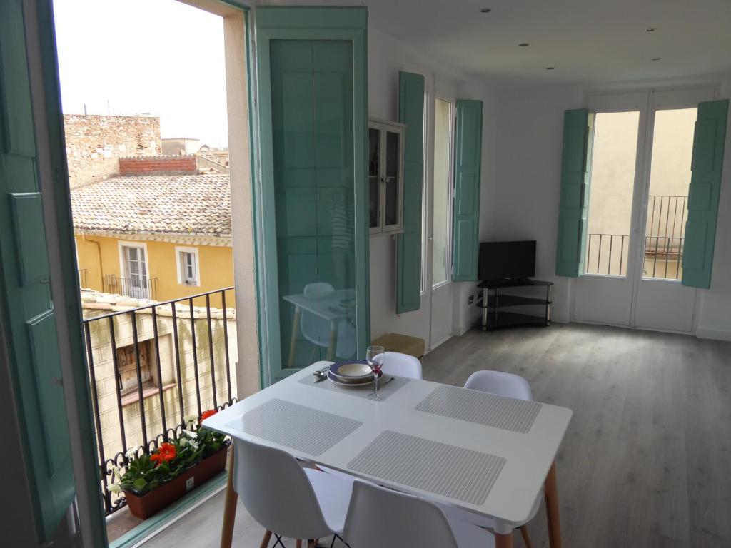 Una mesa blanca y sillas en una habitación con balcón. en Apoteka apartaments, en Figueres