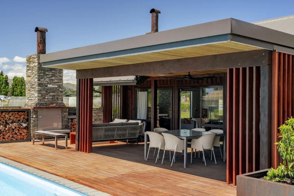 a patio with a table and chairs on a deck at Wanaka Mountain Oasis - Spa & Pool in Wanaka
