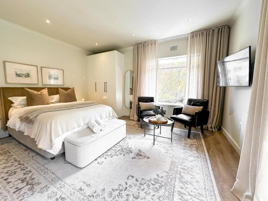 a bedroom with a bed and a chair and a table at Oak Manor Boutique Guest House in Cape Town