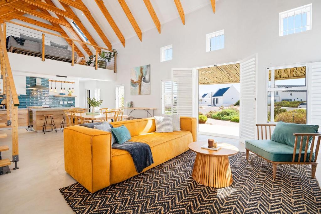 a living room with a yellow couch and a table at Sugarbird in Velddrif
