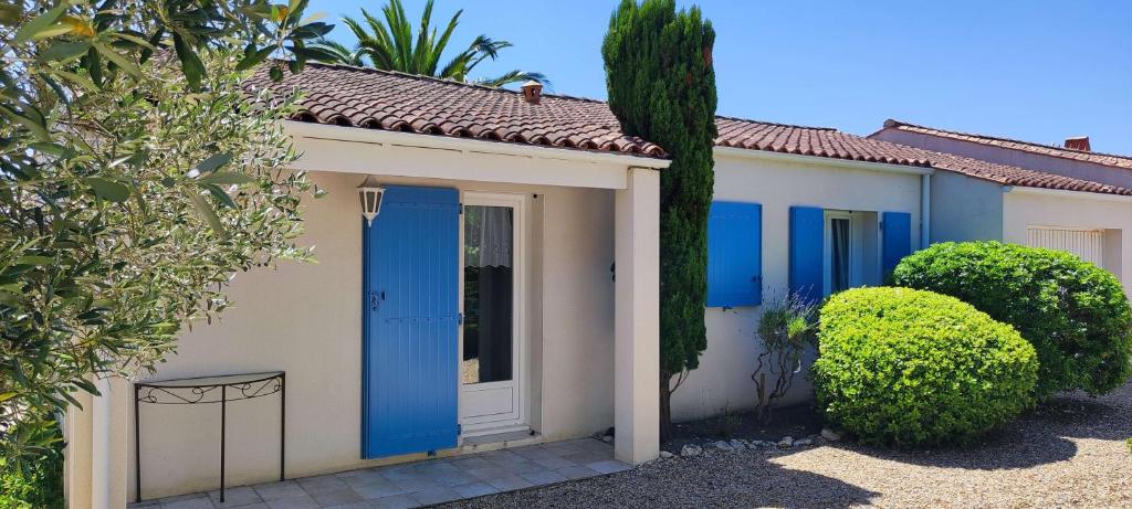 a small house with blue doors and bushes at Maison du Palmier in La Brée-les-Bains