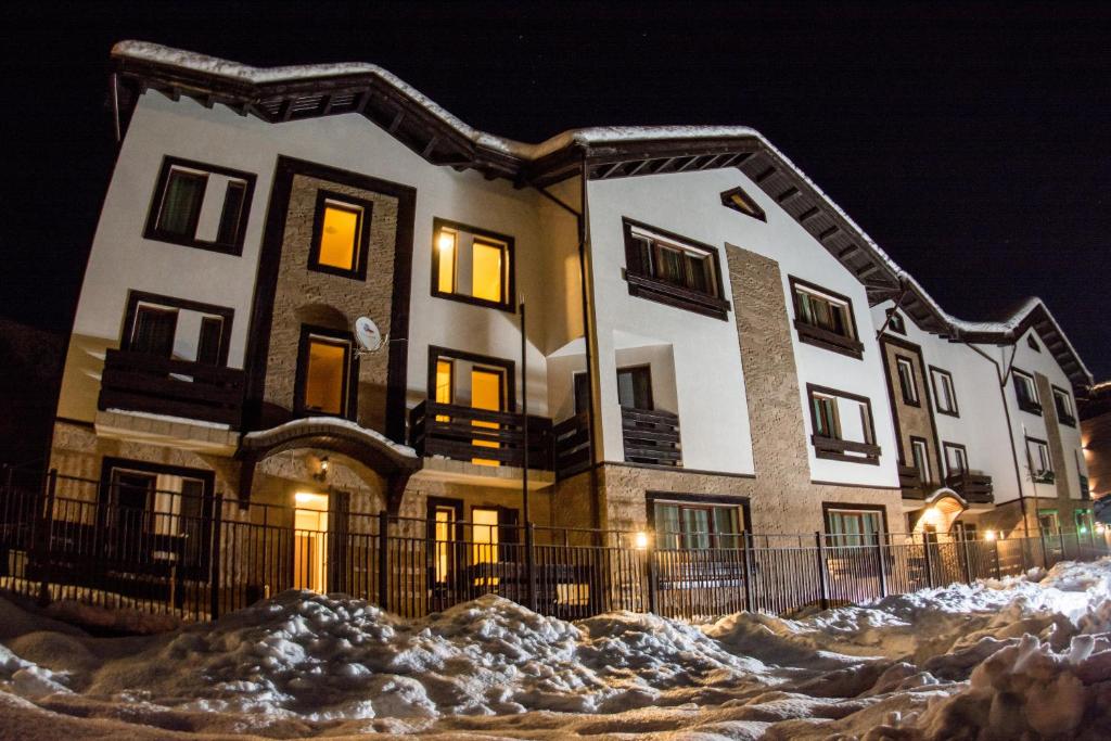 un edificio con nieve delante de él por la noche en Apartments Chudo, en Estosadok