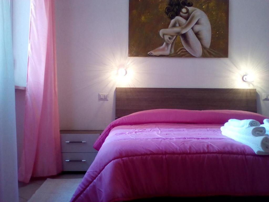 Un dormitorio con una cama rosa con una pintura en la pared en Olbia Center House, en Olbia