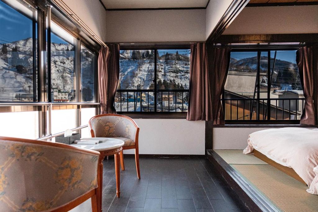 a bedroom with a bed and a table and chairs at 白灯-Hakuto- Ishiuchi in Minami Uonuma