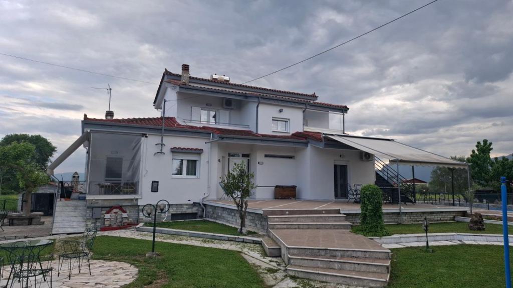 a white house with stairs and a yard at Alesta Apartment in Tríkala