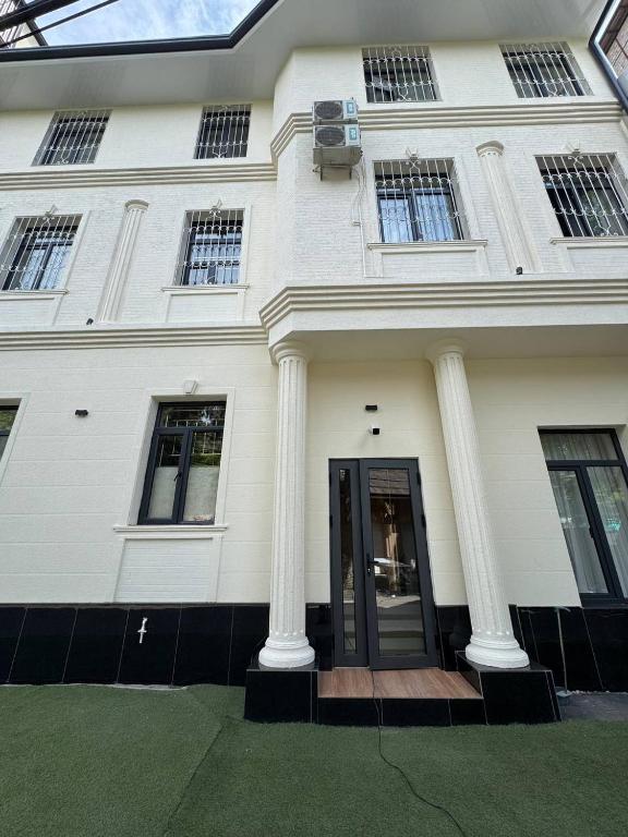 a white house with two columns and a door at Orient Lux in Yakkasaray