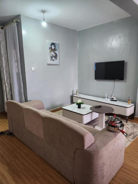 a living room with a couch and a flat screen tv at Zariah Homes 2BR in Kakamega