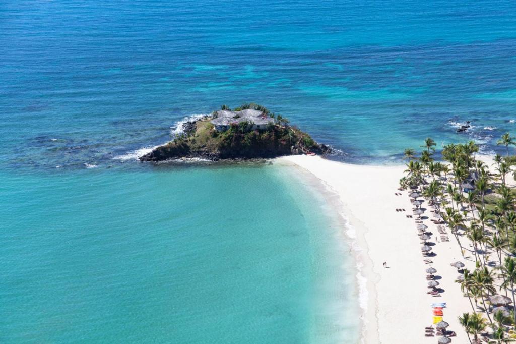an island in the ocean next to a white beach at Maison Carrée Andilana in Andilana