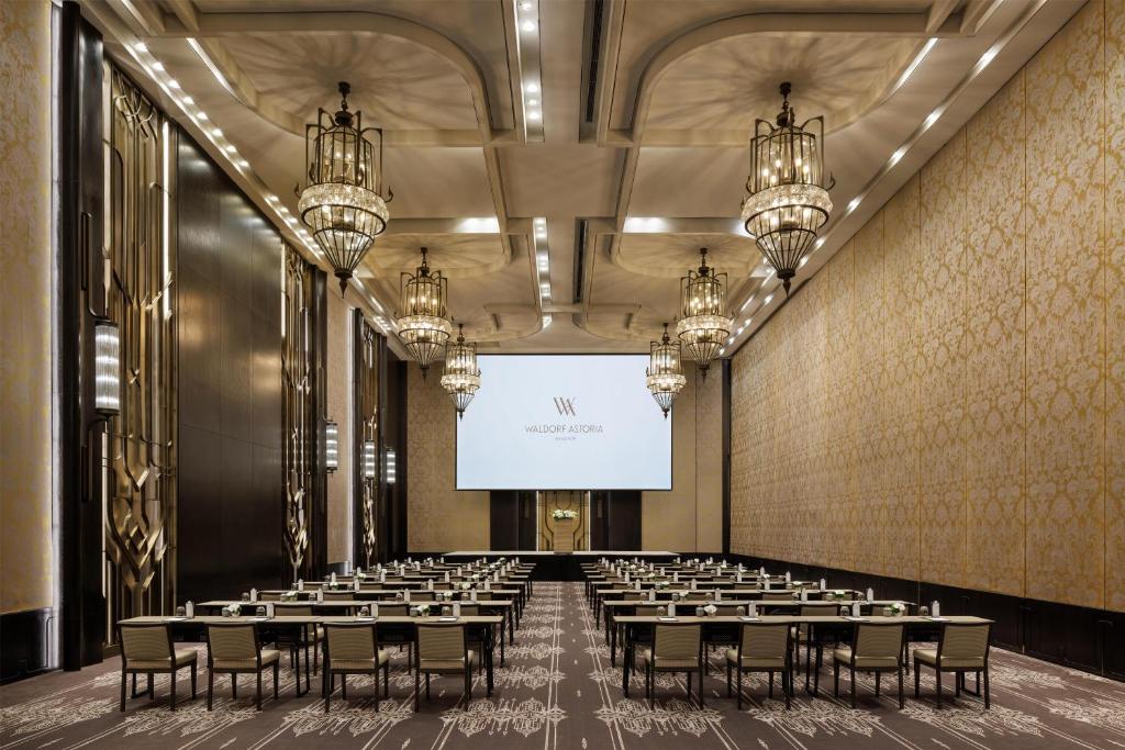 A grand, theatre-style conference hall facing a projection screen.