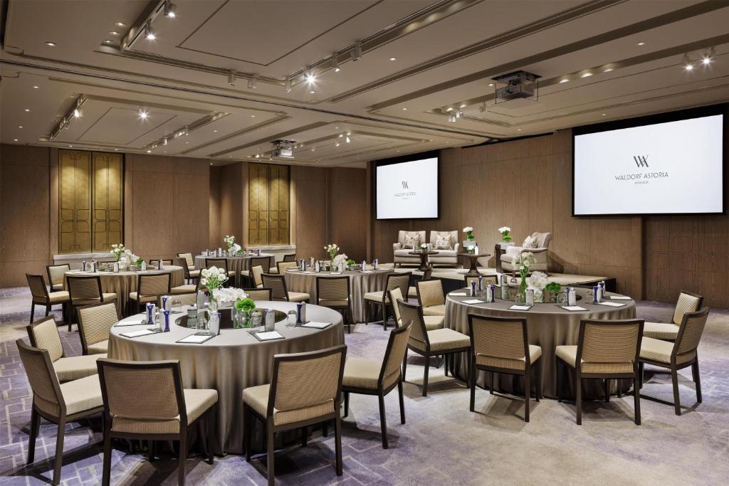 A flexible conference room combining round discussion tables with presentation screens.